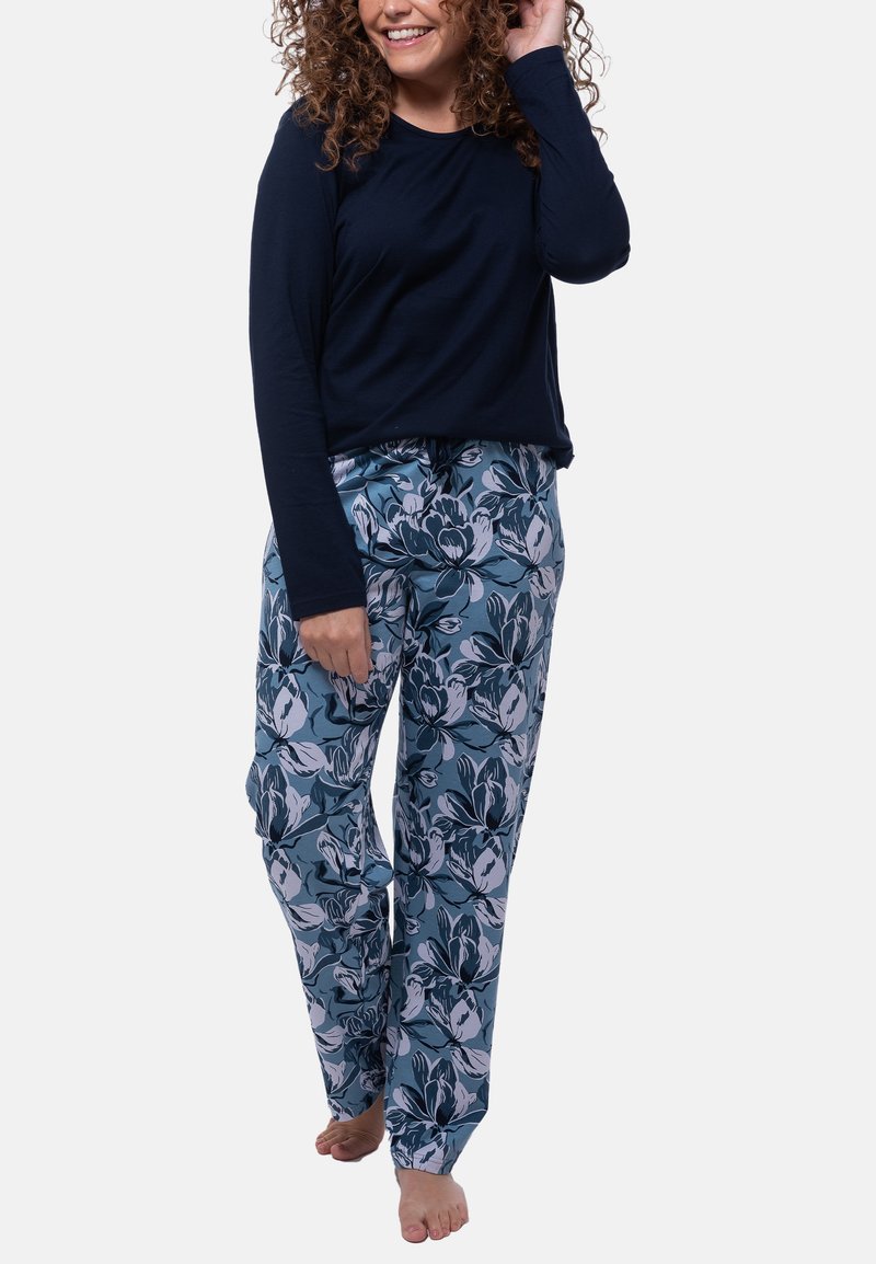 Musta pitkähihaine paita yhdistettynä vaaleansinisiin, kukkakuosisiiin housuihin. Housuissa on nyörivyö ja rento leikkaus.