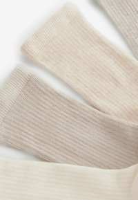 Rebraste čarape u tri boje: svijetlosmeđa, krema i taupe, pokazujući meku teksturu i raznolike nijanse raspoređene u preklapajućim sekcijama.