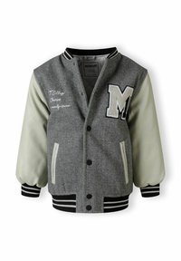 Šedá vlnená varsity bunda s krémovými koženými rukávmi, veľkou nášivkou "M", vyšívanými detailmi a pruhovanými čierno-bielymi rebrovanými manžetami a golierom.