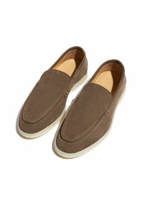 Brune ruskinds slip-on sko med en blød tekstur, rund tå og hvid gummisål. Har syninger langs kanterne for detalje.