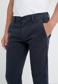 Námořnické modré bavlněné chino kalhoty s úzkým střihem, s knoflíkovým zapínáním, bočními kapsami a hladkým povrchem.