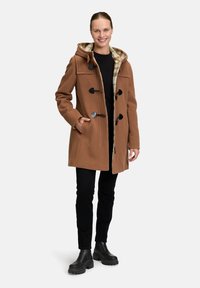 Bruine wollen blend duffle coat met een capuchon, toggle sluitingen en een geruite voering. Gecombineerd met zwarte skinny broek en chunky zwarte laarzen.