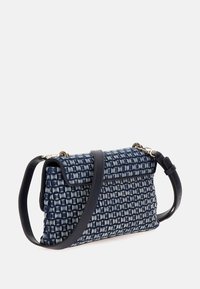 Tkaná taška v námořnické modři s texturovaným mřížkovým vzorem; má tmavý popruh a zlaté kovové detaily.