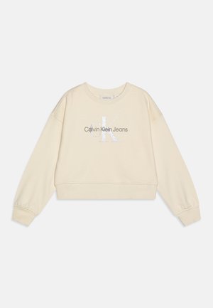 Felpa beige cropped con maniche lunghe, presenta un logo argento "Calvin Klein Jeans" al centro, realizzata in tessuto morbido.