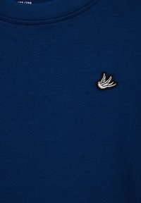 Marineblå sweatshirt med tekstureret stof, der har et lille broderet hvidt fuglelogo på brystet. Klassisk rundhalset design.