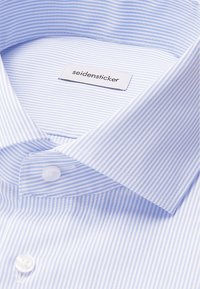 Lichtblauwe en witte gestreepte shirtkraag met een gestikt label "seidensticker" en witte knopen aan de voorkant. Gladde katoenstof.