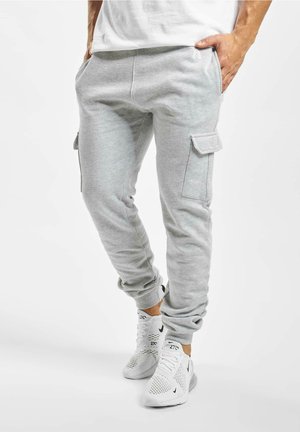Lichtgrijze katoenen sweatpants in een tapered fit, met zijzakken en cargozakken. Gekocht met witte sportschoenen.