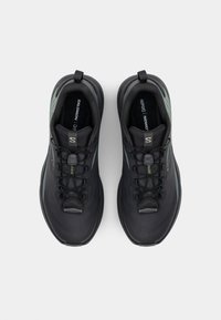 Des chaussures de sport noires avec un dessus texturé, présentant des accents verts et un système de laçage sécurisé. Bout arrondi et semelle rembourrée pour le confort.
