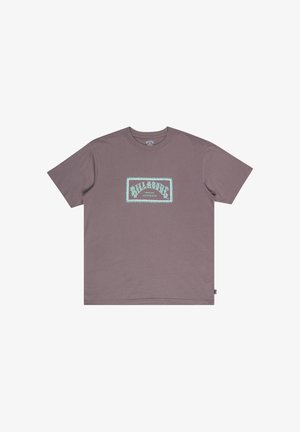 Lilla bomulds T-shirt med et rektangulært lysblåt grafisk motiv med "BILLABONG" tekst og dekorativ kant centreret på fronten. Korte ærmer.