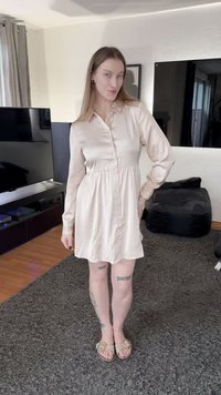 Világos rózsaszín szatén ingruha hosszú ujjakkal, gombos rögzítéssel és húzott derékvezetéssel. Bézs szandálokkal párosítva.