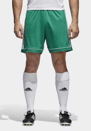 Shorts da calcio verdi con strisce bianche, abbinati a calzettoni bianchi al ginocchio con marchio nero e scarpini da calcio neri con dettagli bianchi.