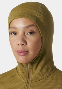 Prenda con capucha de color verde oliva, con un patrón texturizado y acolchado, que presenta un zipper en el cuello y un acabado de tela suave.