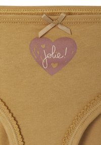 Beiger Stoff mit einer genähten Kante, einem kleinen Satinband und einem lila Herz-Graphic, das den Text "jolie!" mit kleinen Herzen enthält.