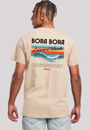 Beige short-sleeve t-shirt with a graphic on the back featuring "BORA BORA" and stylized waves in blue, orange, and green colors.