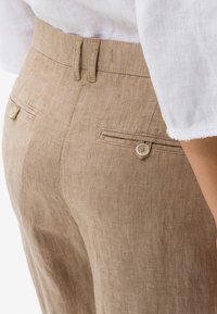 Linnenbyxor i ljusbrun med skräddarsydd passform, med två bakfickor med knäppning och en flat midja.
