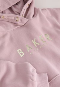 Hellrosa Hoodie mit gold metallic "BAKER BY TED BAKER" Schriftzug und passenden Kordeln mit goldfarbenen Ösen.