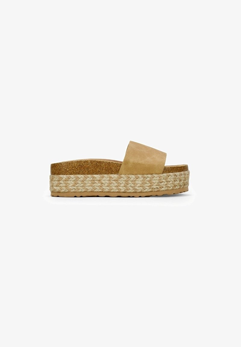 Sandale à plateforme beige avec une large bride, une semelle intermédiaire en jute tissée, une semelle intérieure en liège et une semelle extérieure en caoutchouc texturée.
