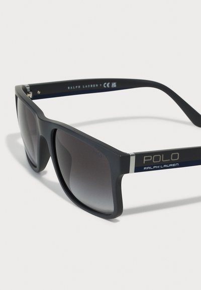 Schwarze Plastiksonnenbrille mit dunklen Verlaufslinsen, dickem Rahmen, silbernen Akzenten und "POLO RALPH LAUREN"-Branding an den Bügeln.
