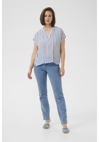 Haut à manches courtes rayé en bleu clair et blanc, avec un décolleté en V. Associé à un jean skinny bleu et des sandales à talons bleu clair.