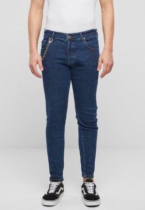 Slim-fit siniset farkut, jotka on valmistettu denimistä. Niissä on vetoketjulla ja napilla suljettava etuosa, viisi taskua ja metalliketjuverhoilu.