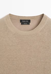 Pull en lin beige à col rond avec col côtelé et étiquette de marque "Massimo Dutti" cousue à l'intérieur de l'encolure.