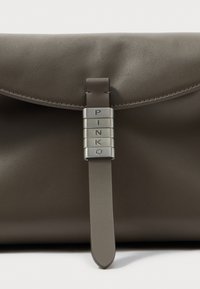 Sivina usnjena torbica z zloženim pokrovom, ki je zavarovana s srebrnim pritrdilnim mehanizmom, na katerem je napis "PINKO." Gladka tekstura.