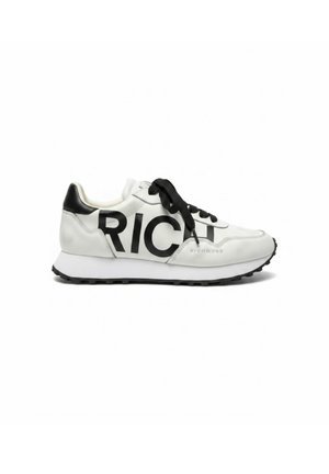 Baskets blanches et noires avec lacets noirs, semelle épaisse et grand lettrage noir "RICH" sur le côté, talon avec accent noir.