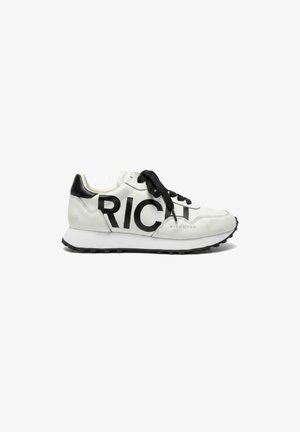 Witte en zwarte sneaker met zwarte veters, dikke zool en grote zwarte "RICH" letters aan de zijkant, hiel met zwarte accenten.