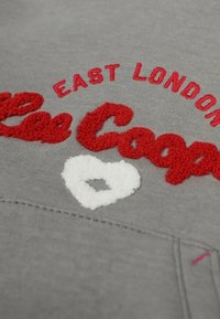 Sweat-shirt gris avec texte brodé en relief rouge et blanc indiquant "East London" et "Lee Cooper", accompagné d'un accent en forme de cœur blanc.