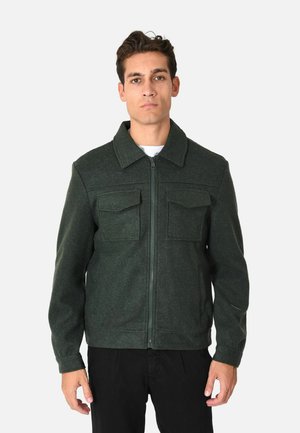 Giacca in misto lana verde con chiusura a zip, due tasche sul petto e colletto classico, realizzata in tessuto texturizzato e con silhouette aderente.