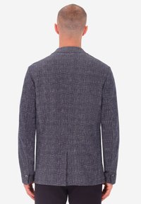 Blazer blu navy con una sottile trama intrecciata, con uno spacco posteriore singolo e polsini con bottoni. Il materiale appare liscio con una vestibilità su misura.