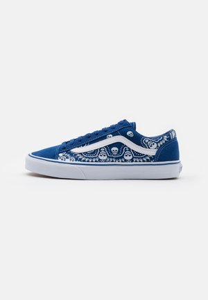 Blauwe lage sneaker met witte zool, witte zijstreep en witte schedel- en paisleypatroondetails op stoffen panelen.