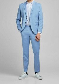 Ljusblå kostym med skräddarsydd passform, med en texturerad tyg. Kombinerad med en mönstrad skjorta och vita sneakers. Justerbara knappar på jackan.