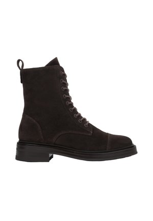 Brązowy zamszowy botek do kostki z okrągłym noskiem, sznurowanym przodem i pętelką z tyłu. Charakteryzuje się grubą, fakturowaną czarną gumową podeszwą.