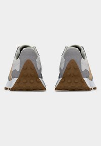 Een paar grijze en beige sneakers met een gestructureerde bruine rubberen hiel en zool, gezien van achteren op een witte achtergrond.