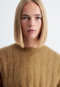 Brauner Mohairpullover mit einem gerippten Muster und einem runden Ausschnitt. Der Stoff wirkt weich und kuschelig und schafft einen warmen und gemütlichen Look.
