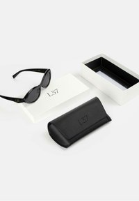 Black oval sunglasses with dark lenses, accompanied by a black leather case and a white box featuring the brand L37 in black lettering.