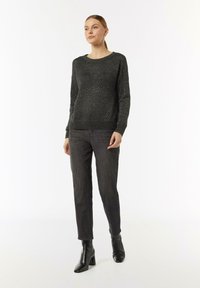 Czarny sweter o fakturze z wzorem w romby, połączony z ciemnoszarymi spodniami slim fit i czarnymi botkami na obcasie. Prosty design i krój.