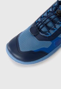 Blue athletic shoe featuring a mesh upper, textured rubber sole, and a rounded toe. Includes a lacing system and contrasting dark accents.