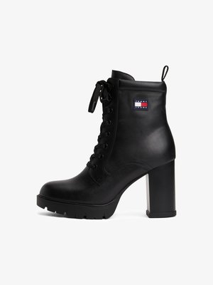 Botim de tornozelo em couro preto com um alto salto bloco, design de amarrar e sola em borracha. Apresenta um emblema da Tommy Jeans de lado.