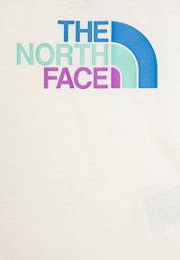 Camiseta de algodón blanca con el logo de "THE NORTH FACE" en azul, verde azulado y púrpura. El diseño incluye un arco parcial sobre el texto.