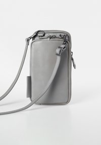 Grau Leder Crossbody-Tasche mit Reißverschluss, verstellbarem Tragegurt und glatter Textur; verfügt über abgerundete Kanten und dezente Nähedetails.