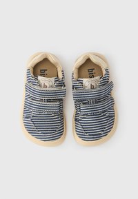 Chaussures en toile bleu marine rayée avec accents beiges, fermeture à scratch, bouts ronds et semelles en caoutchouc clair. Intérieur avec étiquette de la marque.