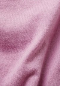 Tissu tricoté rose avec une texture douce et des plis subtils, montrant un motif de fil détaillé et de légères variations de nuances.