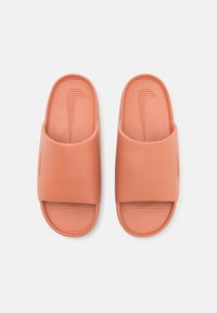 Orange slide sandals made of smooth material with a wide strap and textured footbed. Features a minimalistic design with no visible hardware.