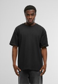 Zwarte oversized t-shirt van katoen, met een ronde hals en korte mouwen, gepresenteerd met een effen, gladde textuur.