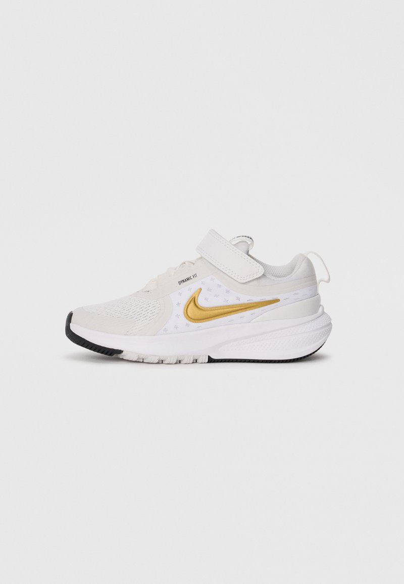 Sneaker atletica bianca e oro con superiore in rete, etichetta Dynamic Fit, cinturino a strappo e suola imbottita con battistrada nero.