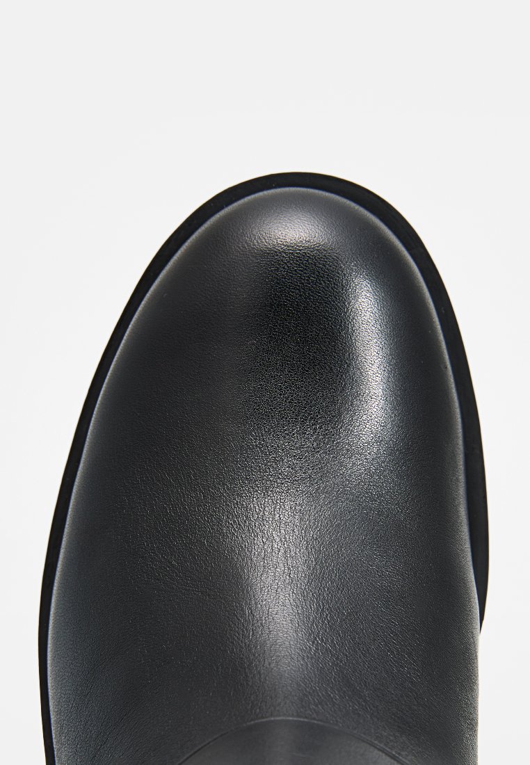 Zwarte leren laars met een ronde neus en een gladde textuur. De zool is plat en heeft een subtiele glans op het bovenoppervlak.