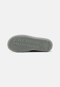 Gray rubber sole with textured pattern, featuring the embossed text "ENERGIA HUMANA" and rounded edge. Flat design suitable for casual wear.