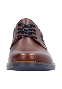 Chaussure habillée en cuir marron avec des lacets navy, bout arrondi et semelle contrastante. Présente des côtés cousus et une finition élégante.